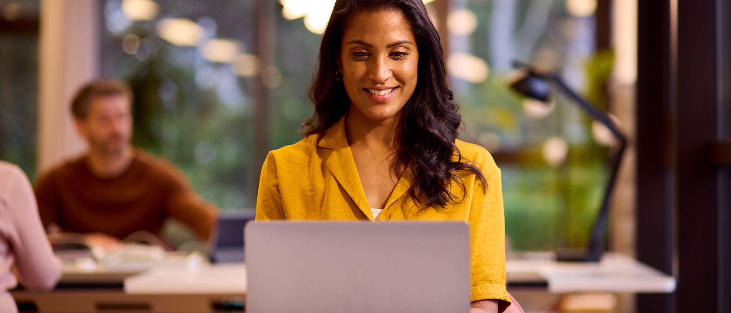 A Brazilian professional working at her laptop in a bright, modern office.