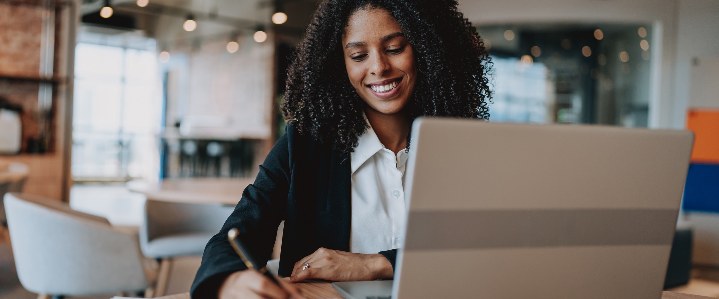A Brazilian professional annotating a chart at her laptop in a modern office.