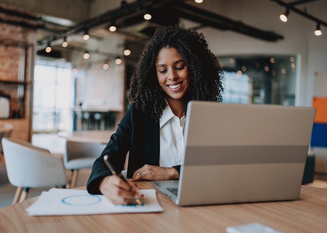 A professional reviewing and annotating analytical documents at her desk